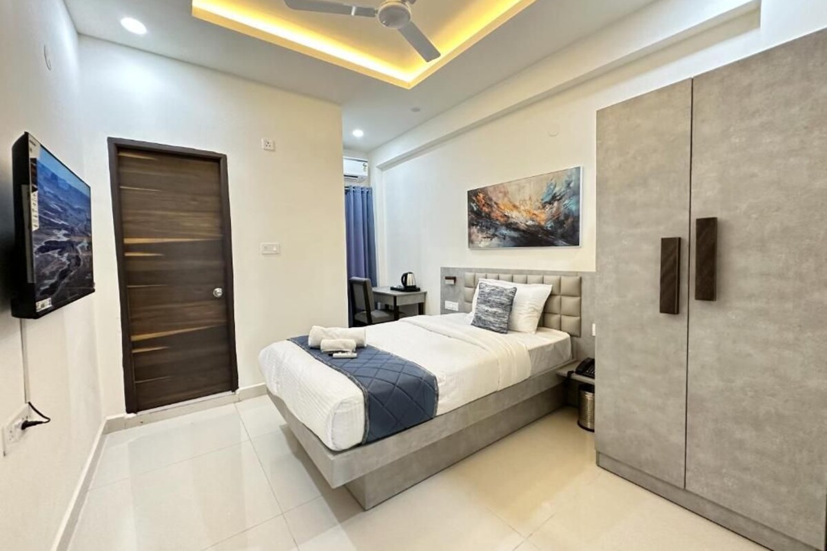 A modern bedroom with a bed, wardrobe, and artwork on the wall.