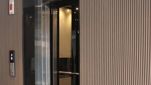 Un ascenseur aux finitions métalliques et un tapis rouge à l’entrée.