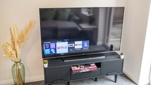 Televisor de pantalla plana sobre un suport negre amb la interfície de Netflix visible.
