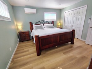 A bedroom with a wooden bed, two bedside tables with lamps, a window, and a door.
