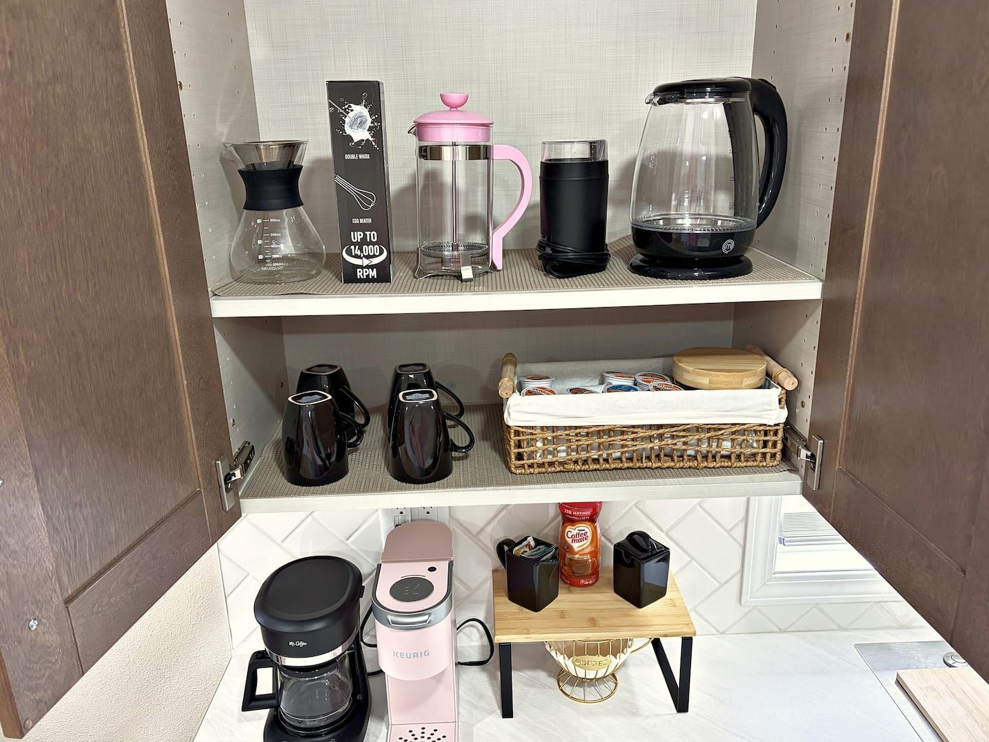 Una cocina americana con cafetera, hervidor, licuadora y molinillo de café sobre la encimera.