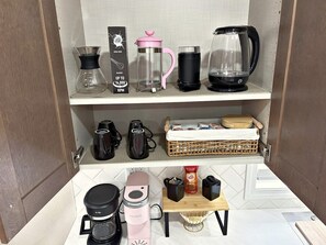 Una cocina americana con cafetera, hervidor, licuadora y molinillo de café sobre la encimera.