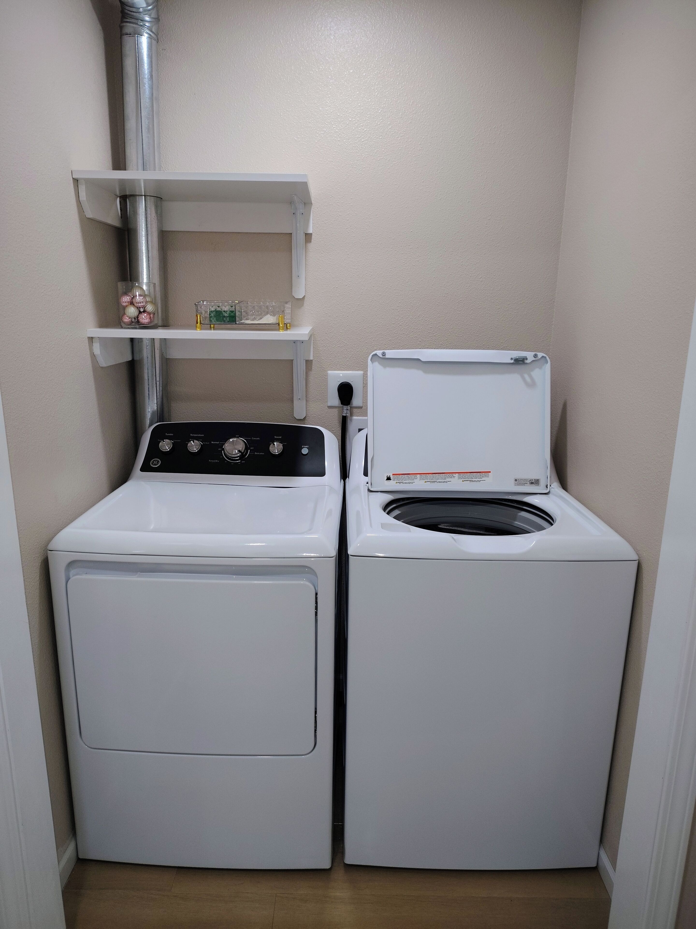 A laundry room with two white front-loading washing machines and a metal pipe above them.