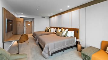 A modern hotel room with two beds, a desk, a chair, and a small table.