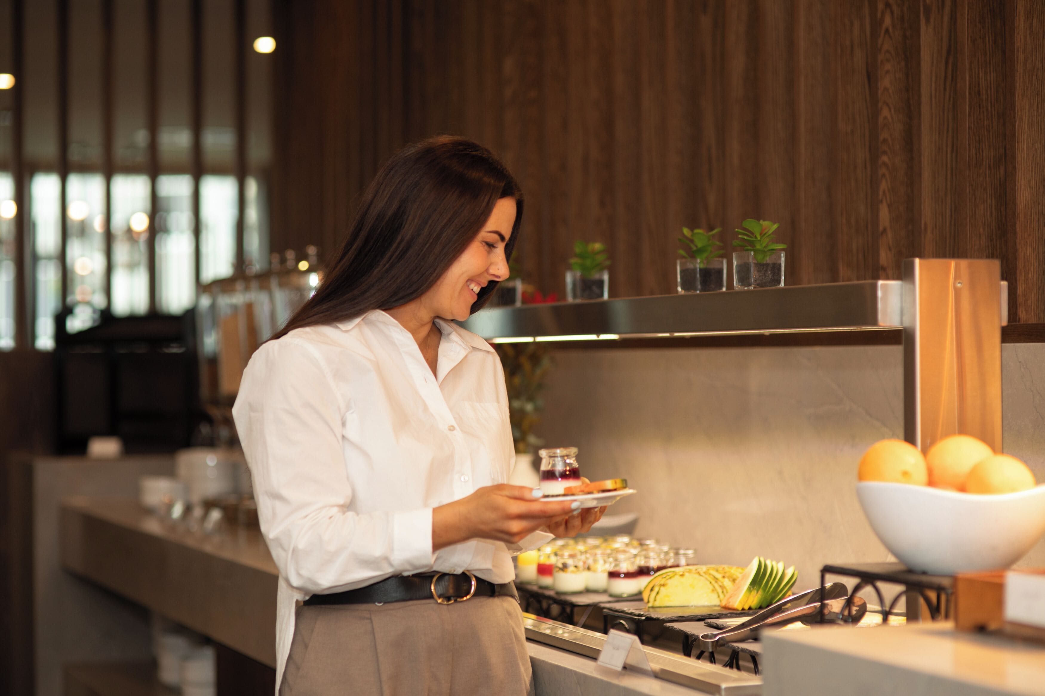 A person serving food in a modern kitchen with wooden accents and a visible stove.