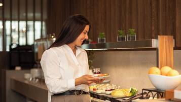 A person serving food in a modern kitchen with wooden accents and a visible stove.