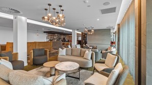 A modern lounge area with sofas, armchairs, and a bar in the background. - Distinction Invercargill Hotel (Invercargill)