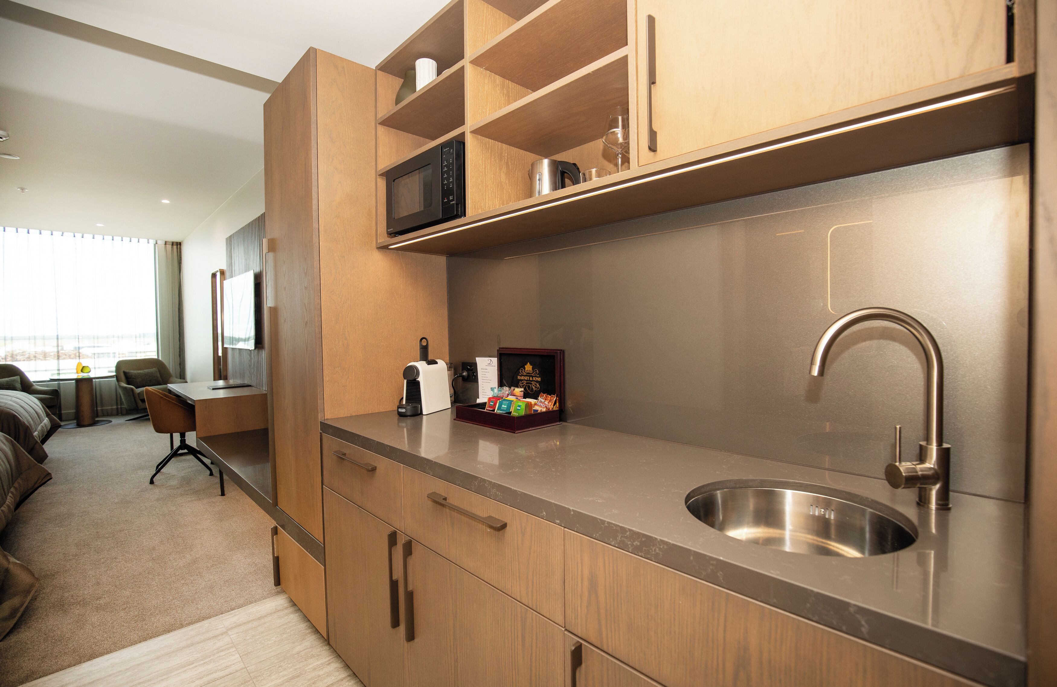 A modern kitchen with wooden cabinets, a stainless steel sink, and a microwave.