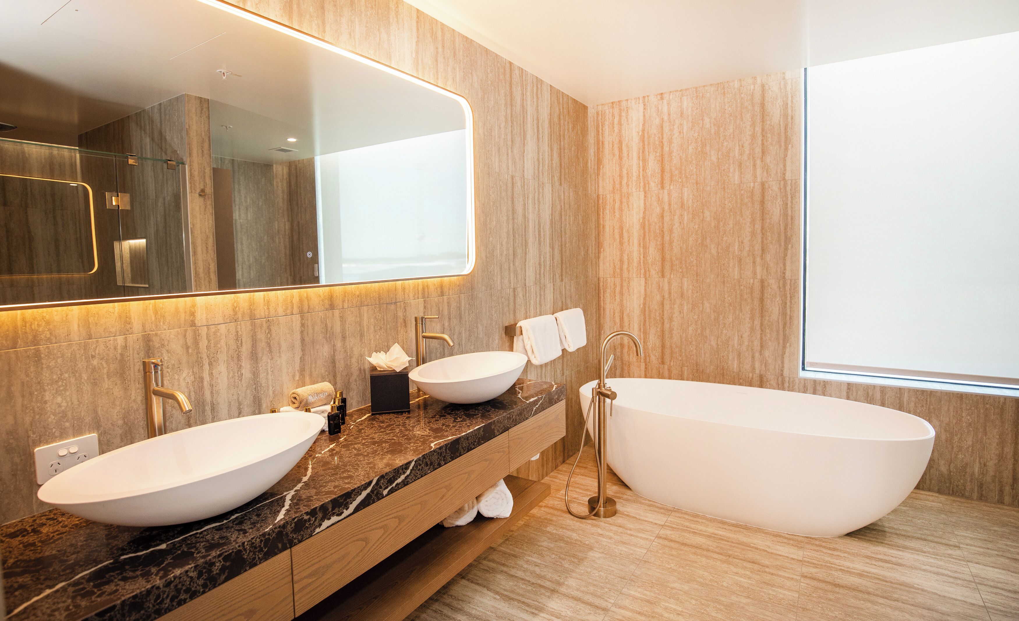 Une salle de bain moderne avec deux vasques, une grande baignoire et un miroir au-dessus du meuble-lavabo.