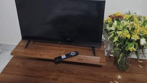 Un téléviseur à écran plat posé sur un meuble en bois, avec une télécommande à côté.