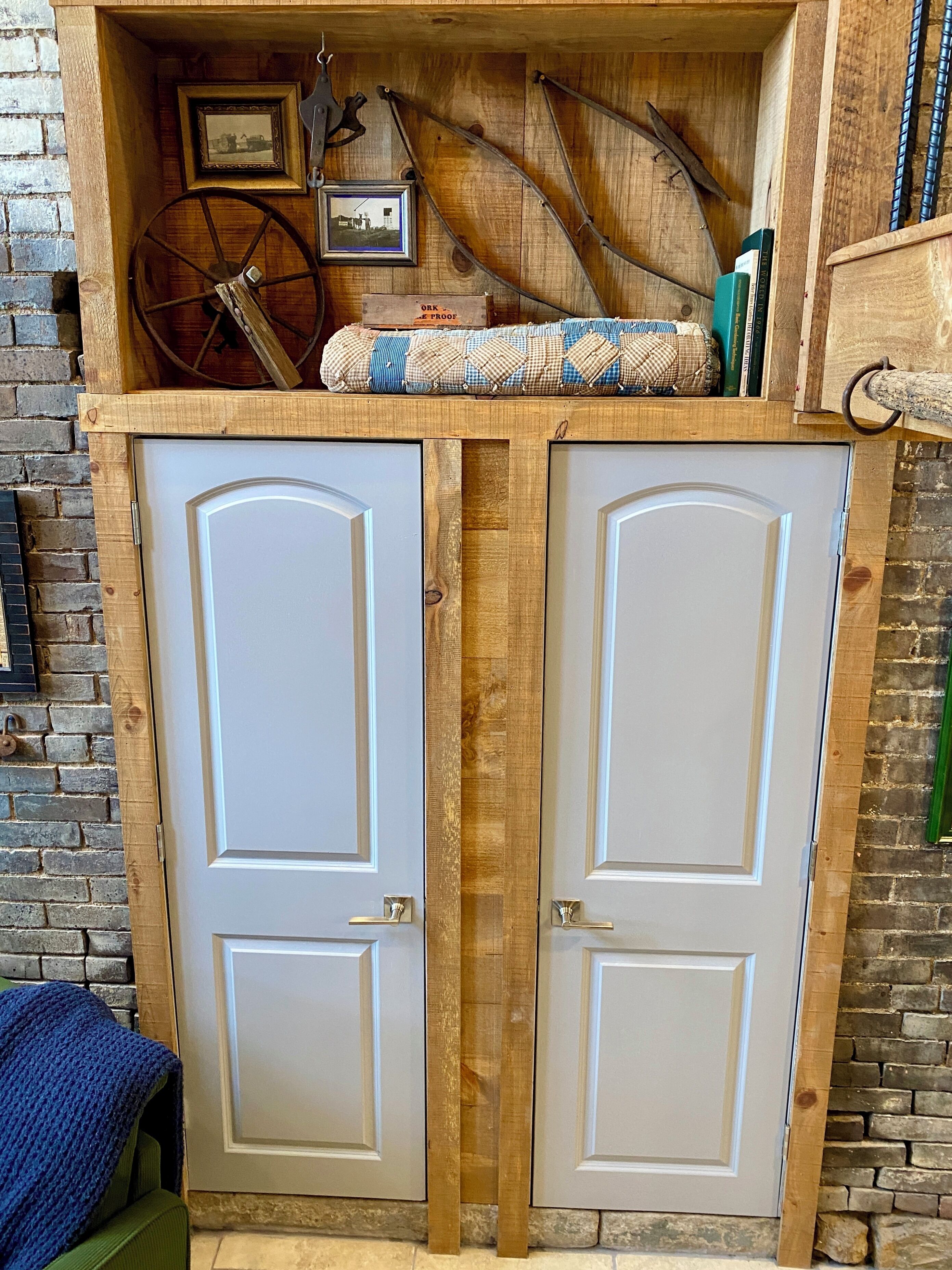 Un armario de madera con dos puertas, un estante superior con una cámara antigua, un cuadro enmarcado y una alfombra pequeña.