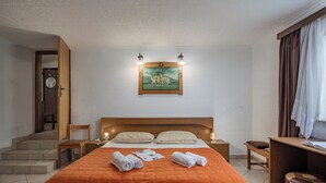 Habitación de hotel con una cama grande, un escritorio, una silla, una mesita de noche, un reloj de pared y un cuadro enmarcado sobre la cama.