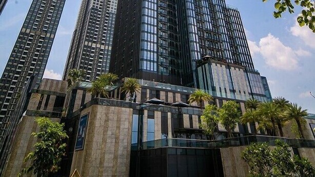 Um arranha-céu alto e moderno com fachada de vidro, cercado por outros edifícios altos.