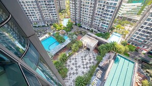 Um edifício residencial alto com várias varandas, uma piscina e um pátio ajardinado.