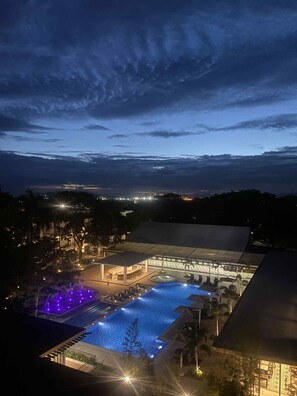 A resort with a large swimming pool, a covered area with seating, and a view of the surrounding landscape.