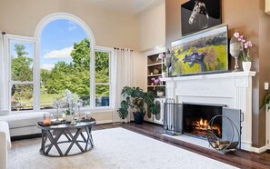 A living room with a fireplace, large windows, and a view of the outdoors.