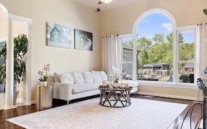 A spacious living room with a large window, a white sofa, and a coffee table.
