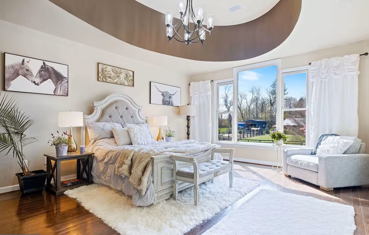 A bedroom with a large bed, a sitting area with a chair, and a view of the outdoors.