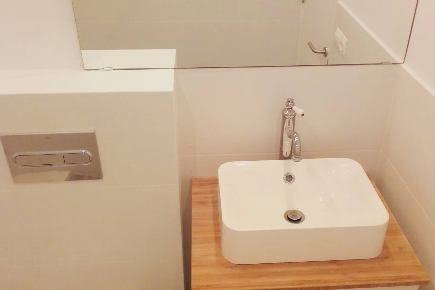 A bathroom with a white sink, a mirror above it, and a wooden countertop.
