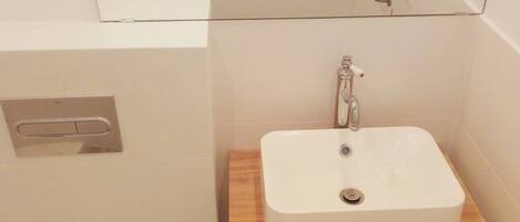 A bathroom with a white sink, a mirror above it, and a wooden countertop.