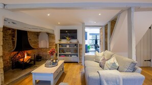 Una sala de estar acogedora con chimenea de piedra, un sofá blanco y una mesa de centro de madera.