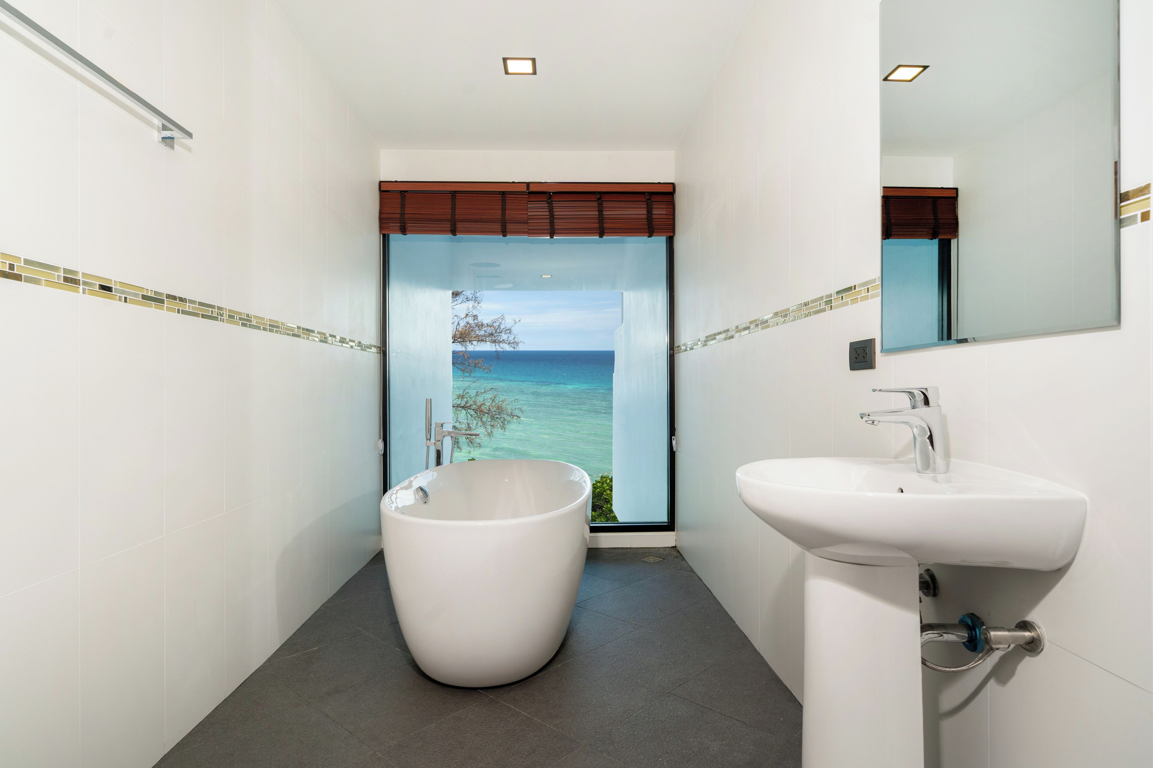 Un baño con una bañera grande, un lavabo y vista al océano.