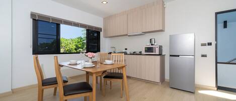 A modern kitchen with wooden cabinets, a stainless steel refrigerator, and a dining area with a table and chairs.