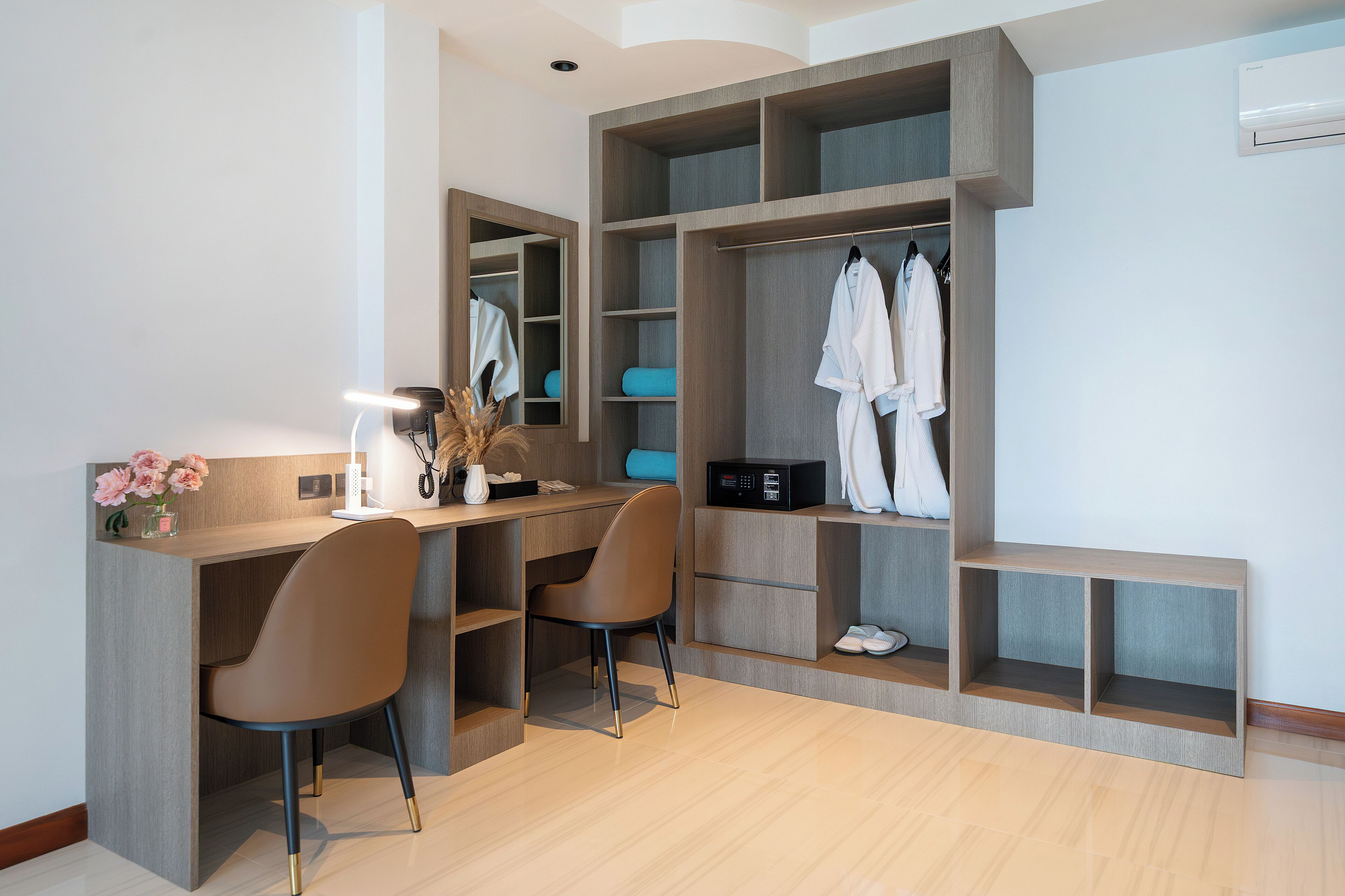 A modern room with a built-in desk, two chairs, a mirror, and a walk-in closet with shelves and hanging space.