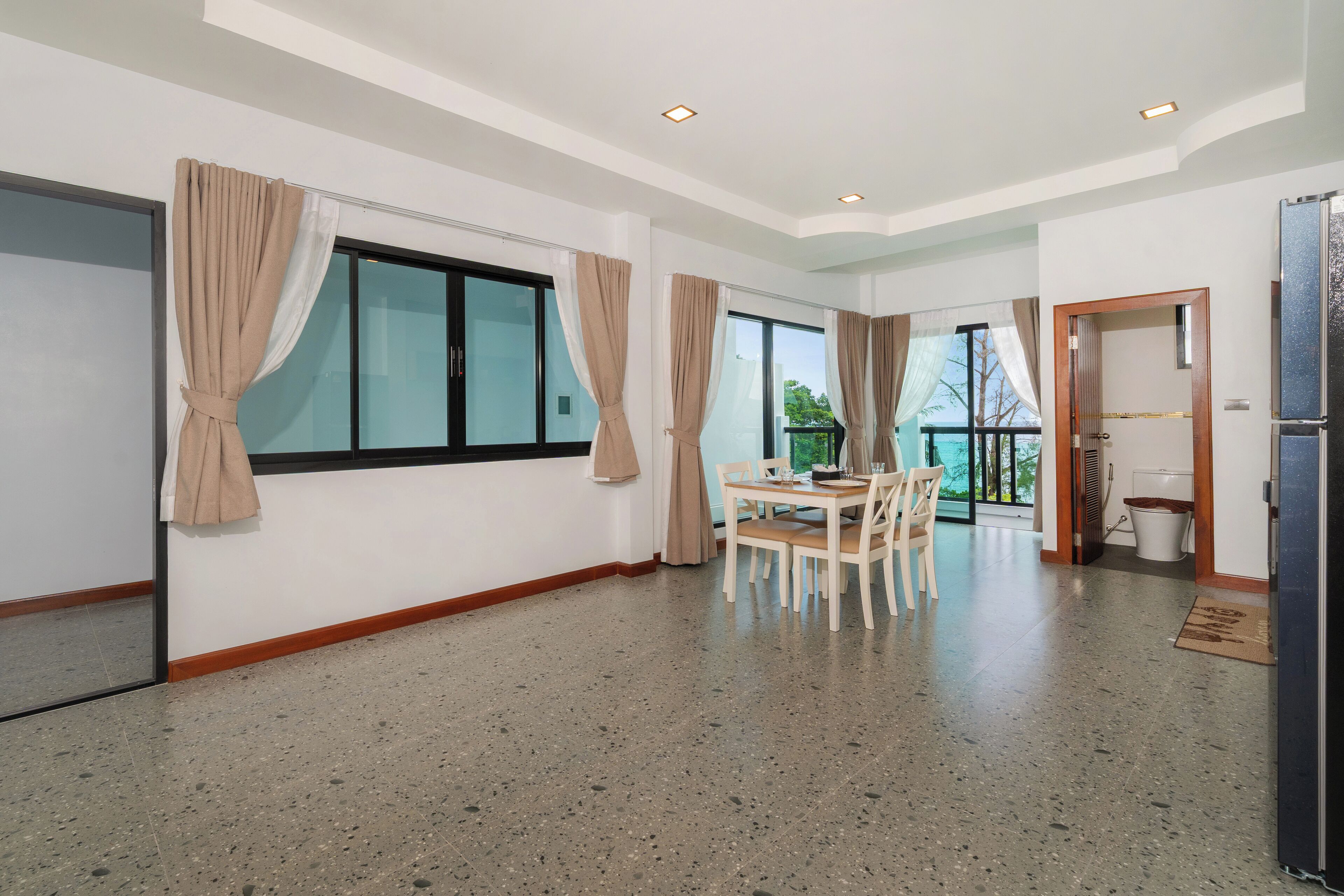 Una habitación amplia con una mesa de comedor, sillas, un ventanal con cortinas y vistas al exterior.
