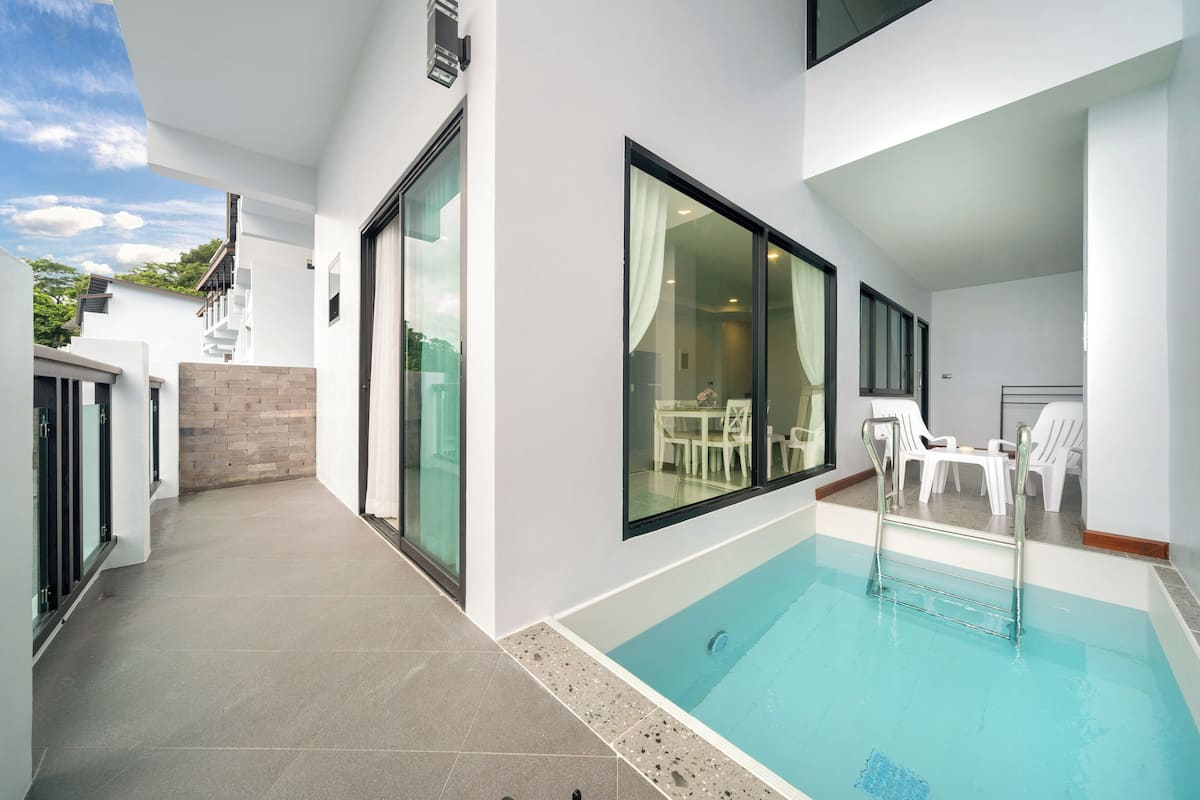 A modern indoor swimming pool with glass walls, a clear view of the adjacent dining area, and a tiled floor.