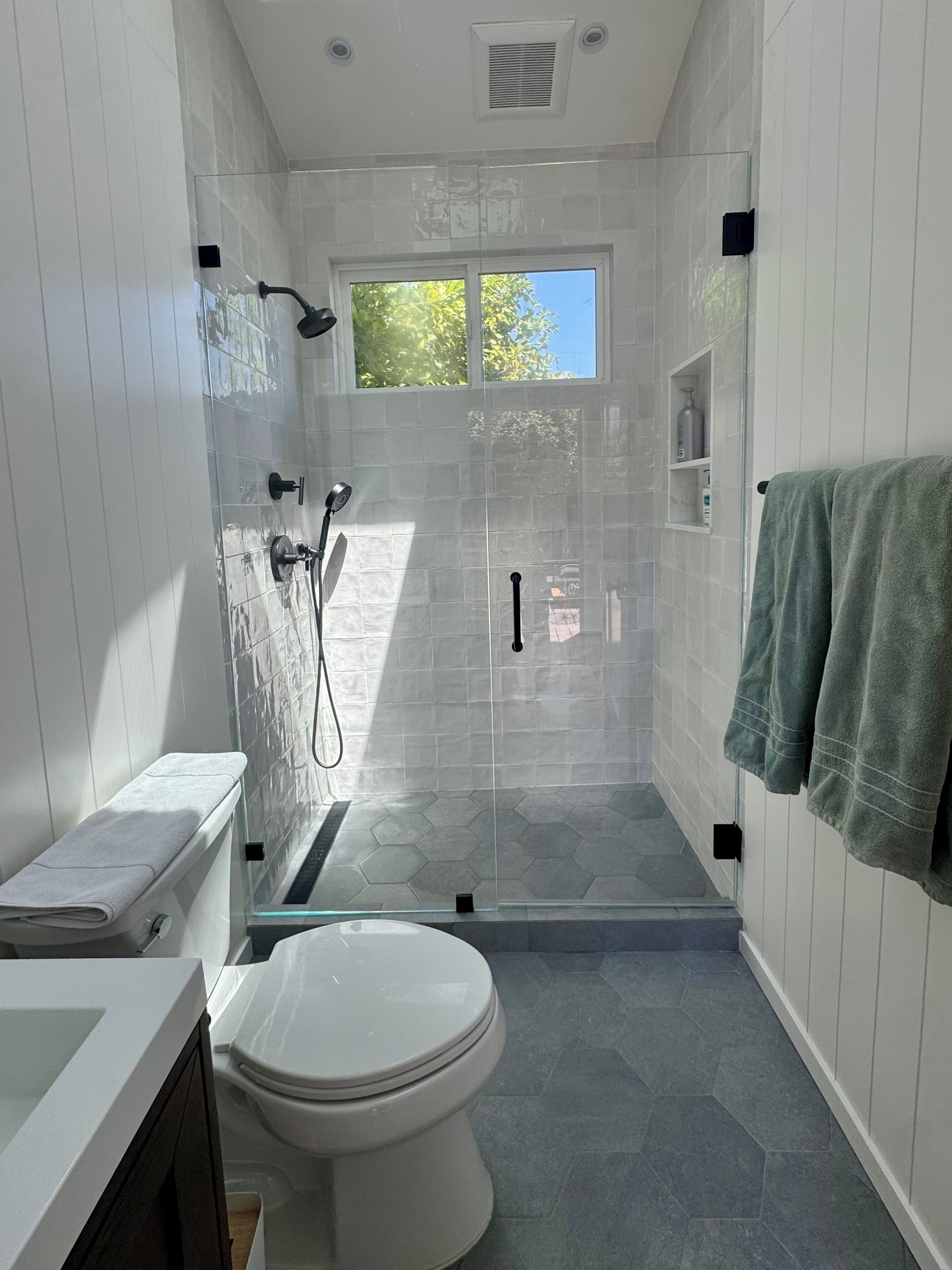 A modern bathroom with a glass shower enclosure, a toilet, and a sink.