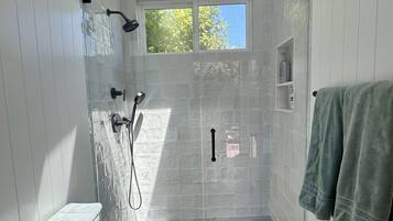 A modern bathroom with a glass shower enclosure, a toilet, and a sink.