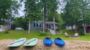 A sandy beach with kayaks and a house in the background.