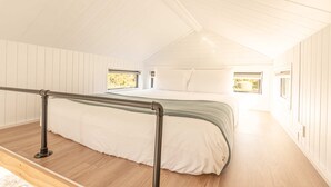 Une chambre à coucher avec un lit, une fenêtre et un plancher en bois.