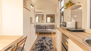 Une cuisine compacte équipée d’un four à micro-ondes, d’un ordinateur portable posé sur le plan de travail et d’un petit évier.