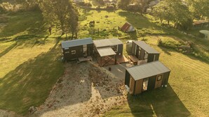 Une maison moderne et compacte, dotée d’une grande terrasse, entourée d’un paysage verdoyant luxuriant et surplombant un village situé au loin.