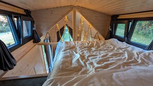 Una habitación acogedora con cama, ventanas amplias y vistas al exterior.