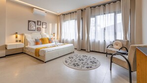 Ein modernes Schlafzimmer mit Bett, Nachttischen, einem Sessel und einem runden Teppich.