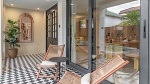 Ein modernes Interieur mit einem Schachbrettfußboden, einer großen Glasdoor zu einem Essbereich und einer Topfpflanze.