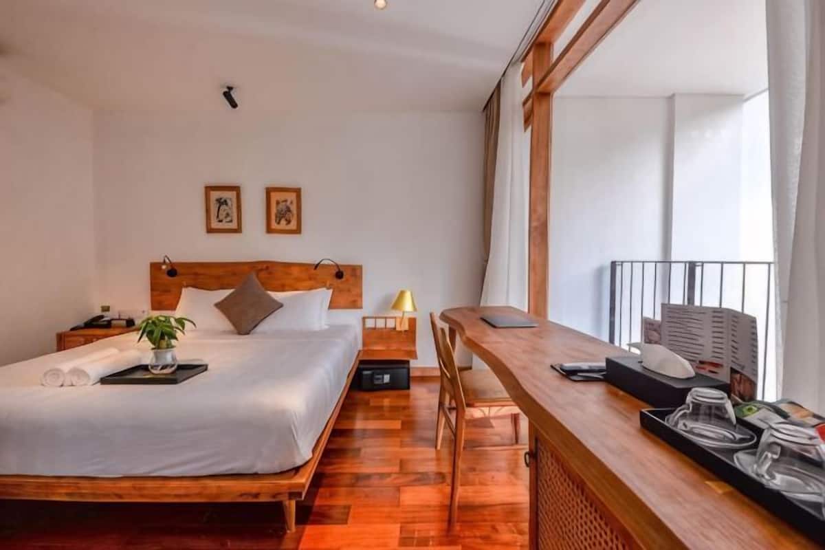 Ein Schlafzimmer mit einem Holzbett, Nachttischen, einem Schreibtisch und einem großen Fenster.