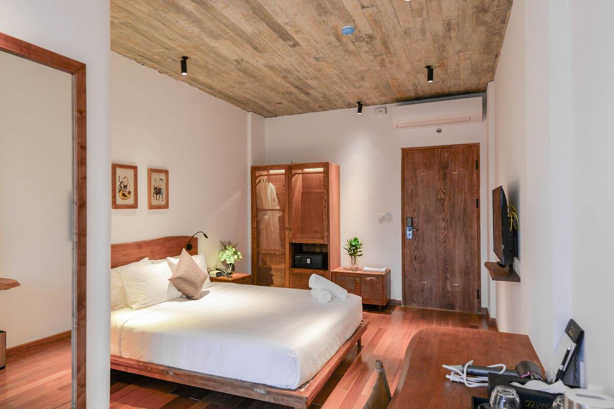 Ein Schlafzimmer mit einem hölzernen Bett, einem Nachttisch, einem Kleiderschrank und einem an der Wand befestigten Fernseher.