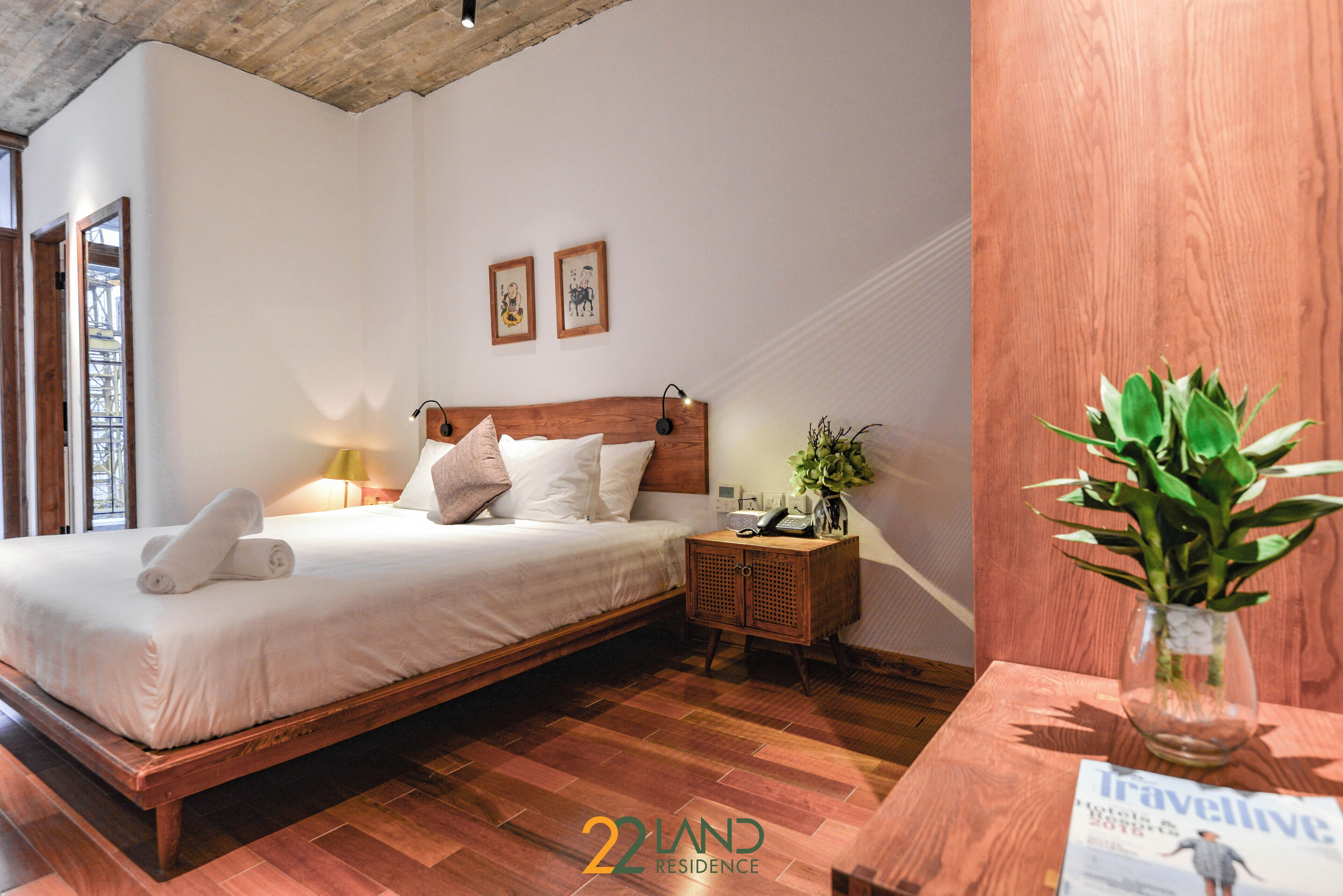 A bedroom with a wooden bed, a nightstand, a lamp, and a plant.