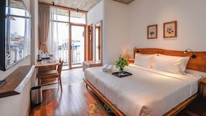 A bedroom with a wooden bed, a desk, and a view of the city through large windows. - 22 Land 50 Truong Cong Giai Hotel (Hanoi)