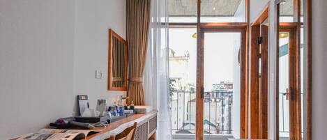 Cocina compacta con encimera de madera, un lavamanos y una ventana con cortinas.