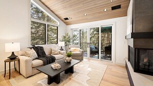A modern living room with a fireplace, large windows, and a cozy seating area.