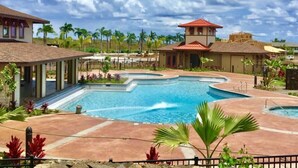 Un complexe hôtelier doté d’une grande piscine, de palmiers et d’un bâtiment au toit rouge.