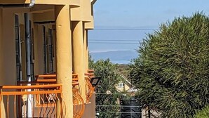 A yellow building with a balcony and a view of a green hedge and a house in the background. - Lux Suites Sunset Delight Holiday Homes (Naivasha)