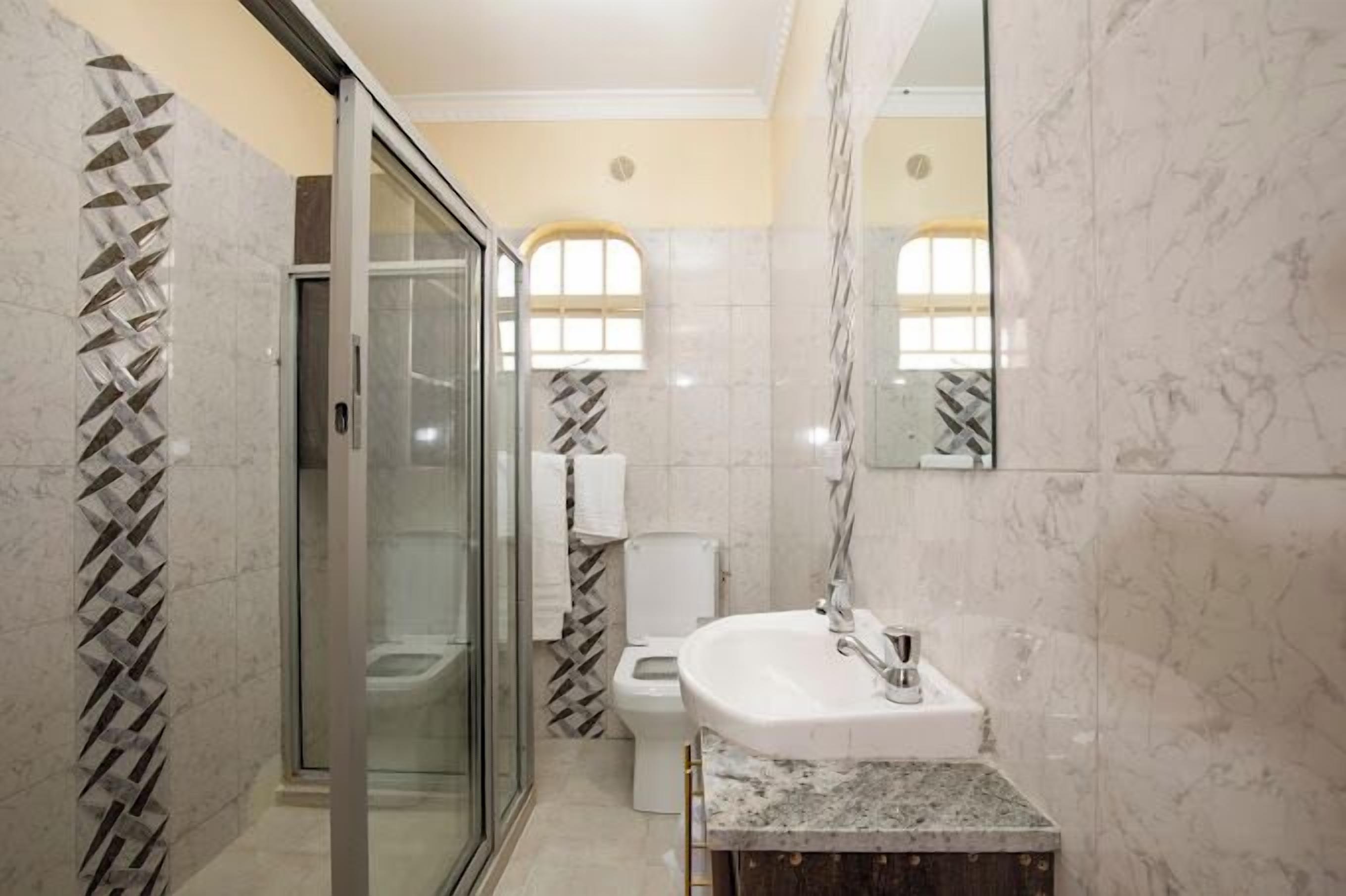 Un baño con cabina de ducha de vidrio, un lavabo blanco y un inodoro.