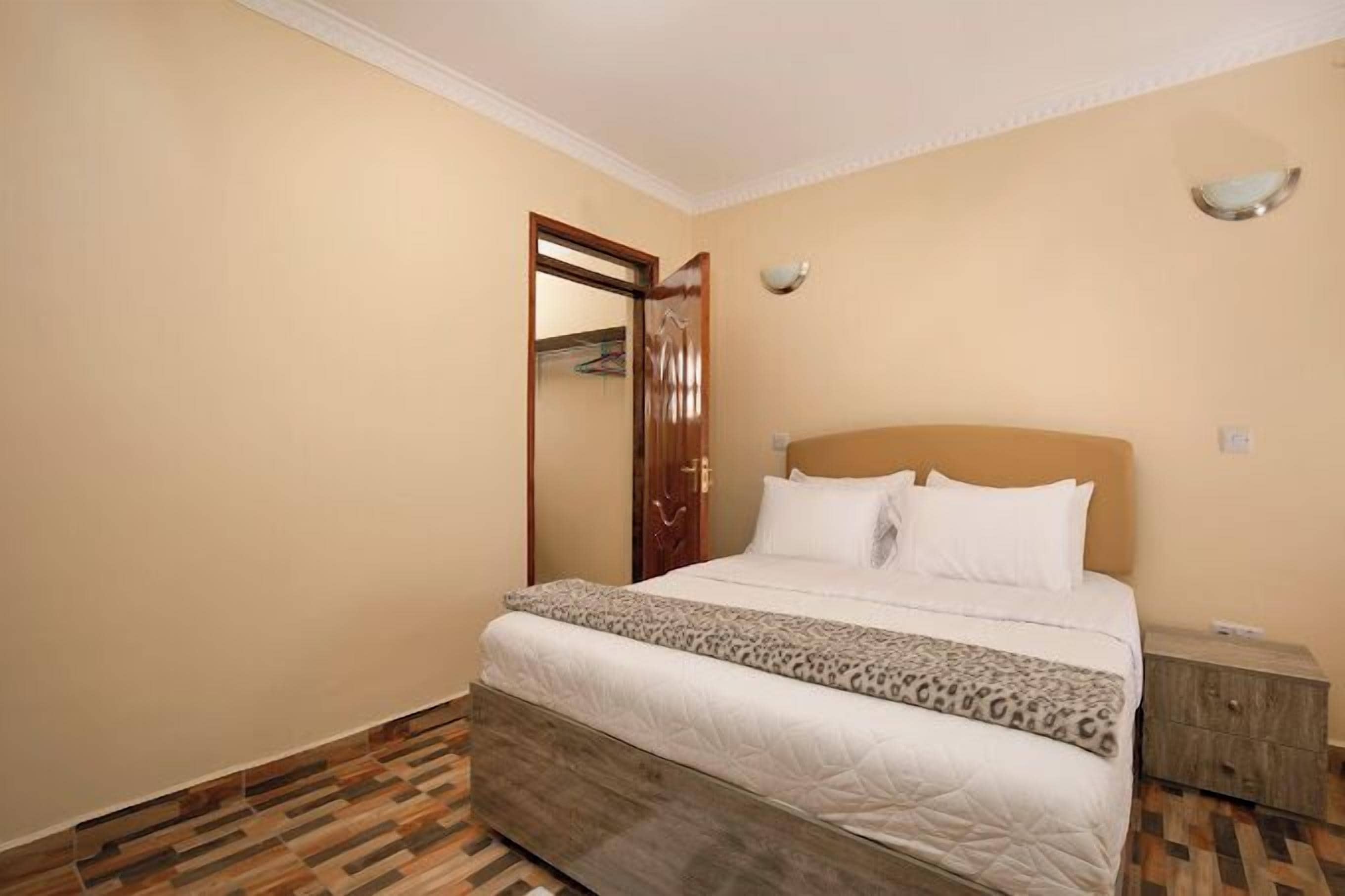 A bedroom with a bed, a wooden headboard, a nightstand, and a wardrobe.