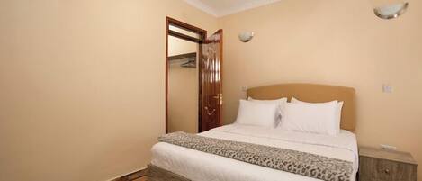 A bedroom with a bed, a wooden headboard, a nightstand, and a wardrobe.
